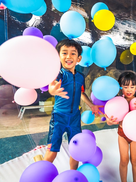 Children playing with colorful balloons at Adventure Cove Waterpark™.