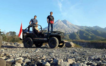 Jeep tour at Mount Merapi with three people, rocky terrain, and mountain view in the background.