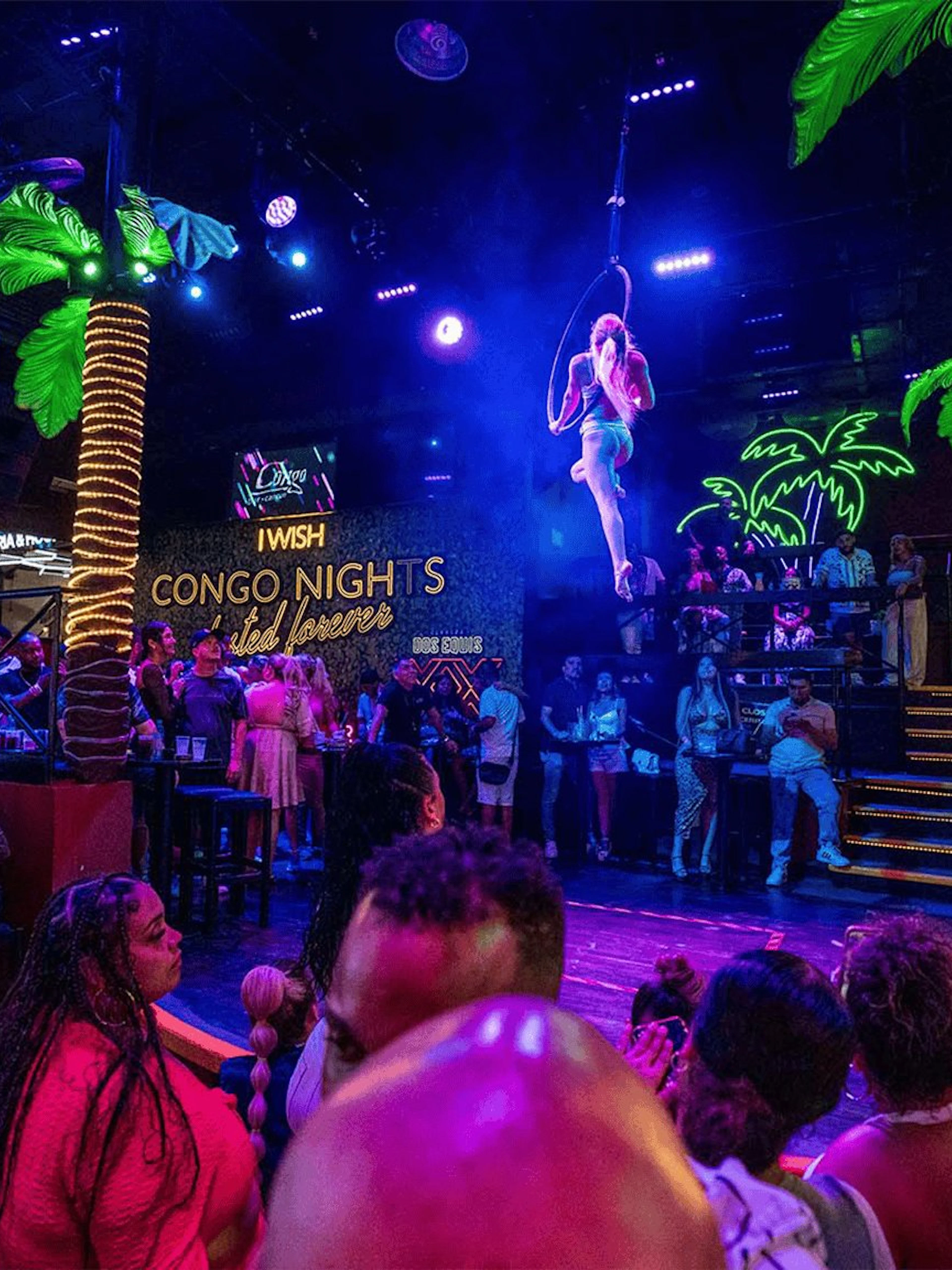 Crowd enjoying a vibrant night show at Coco Bongo Congo Bar with acrobatics and neon lights.