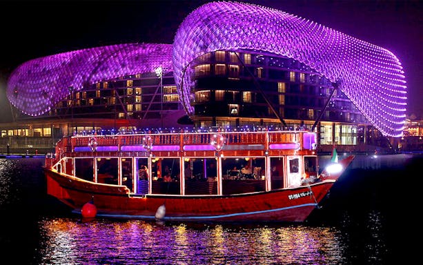 Dhow cruise with lights on water near illuminated Yas Hotel, Abu Dhabi.