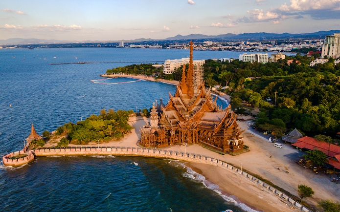 Aerial view of the Sanctuary of Truth wooden temple in Pattaya, Thailand at sunset.