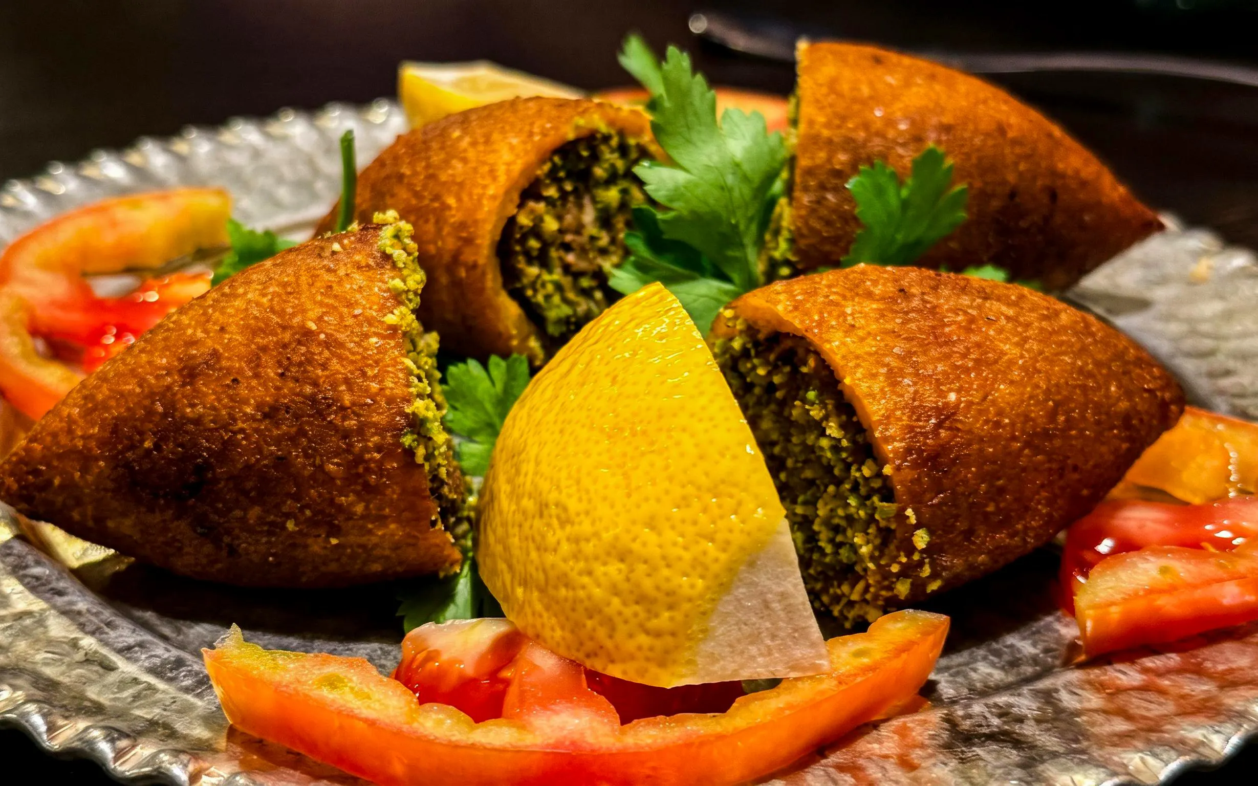 Kibbeh with lemon and tomato slices on a plate, Istanbul Food Tour.