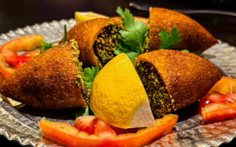 Kibbeh with lemon and tomato slices on a plate, Istanbul Food Tour.