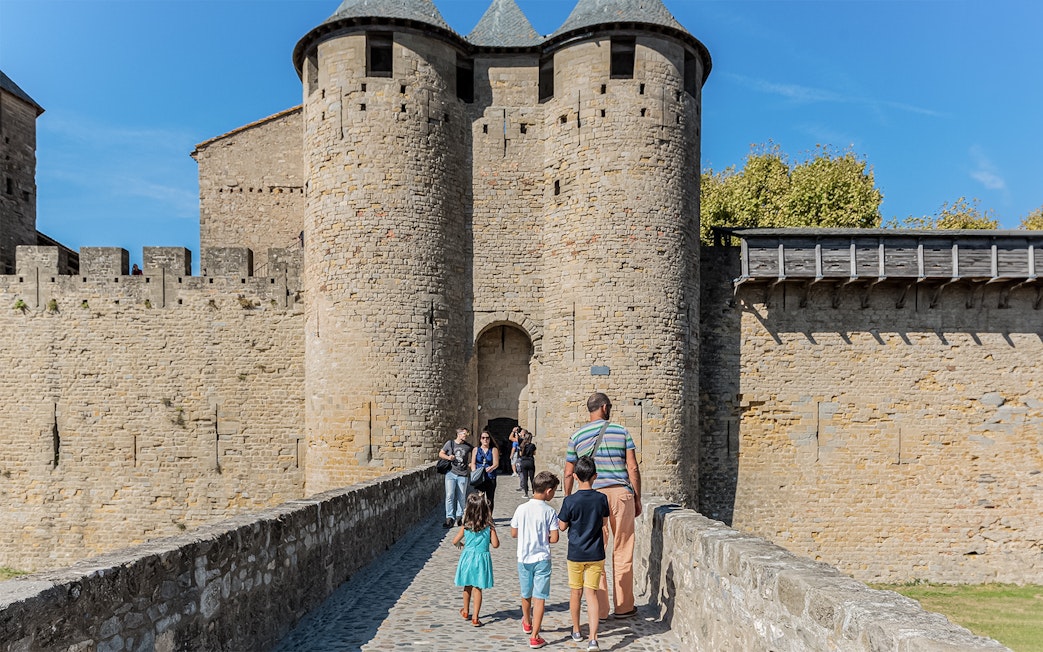 Visitors walking towards the entrance of Comtal Castle, Cité de Carcassonne, UNESCO site.