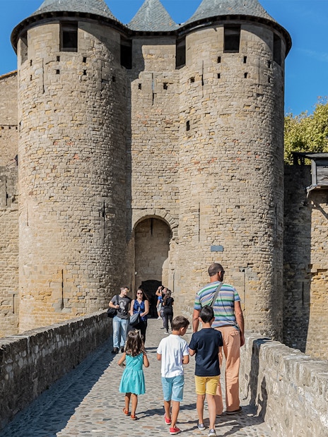 Visitors walking towards the entrance of Comtal Castle, Cité de Carcassonne, UNESCO site.