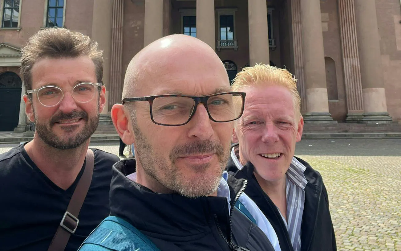 Three people in front of a historic building in Copenhagen during a self-guided city exploration game.