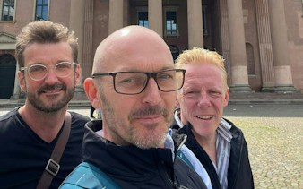 Three people in front of a historic building in Copenhagen during a self-guided city exploration game.