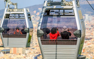 Montjuic cable cars with passengers overlooking Barcelona cityscape.