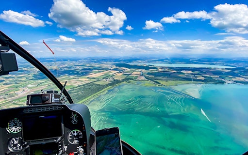 Helicopter cockpit view over Bernese Seeland and Jura landscape.