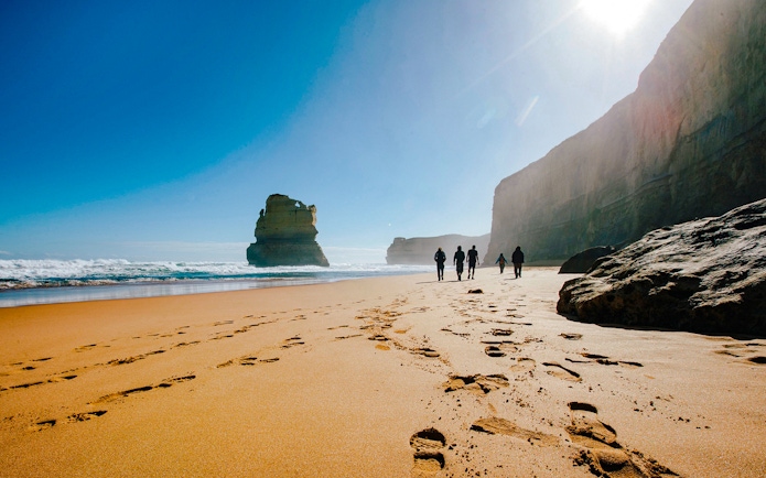 Tourists walking along Gibson Steps beach on the Full Day Great Ocean Road Guided Tour.