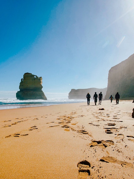 Tourists walking along Gibson Steps beach on the Full Day Great Ocean Road Guided Tour.