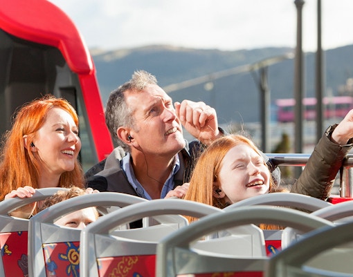 A family of three in a Hop On Hop Off bus, seeing attractions on their way