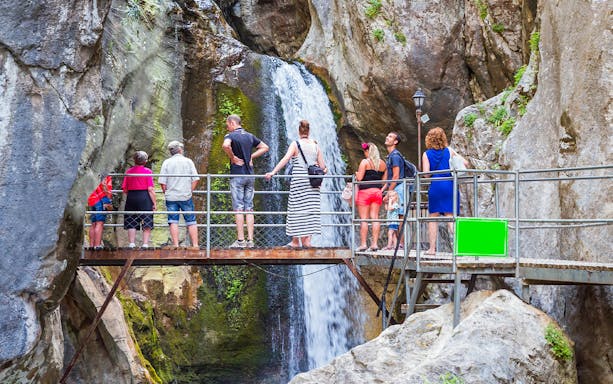 Visitors on a bridge viewing a waterfall during a family rafting tour from Antalya.