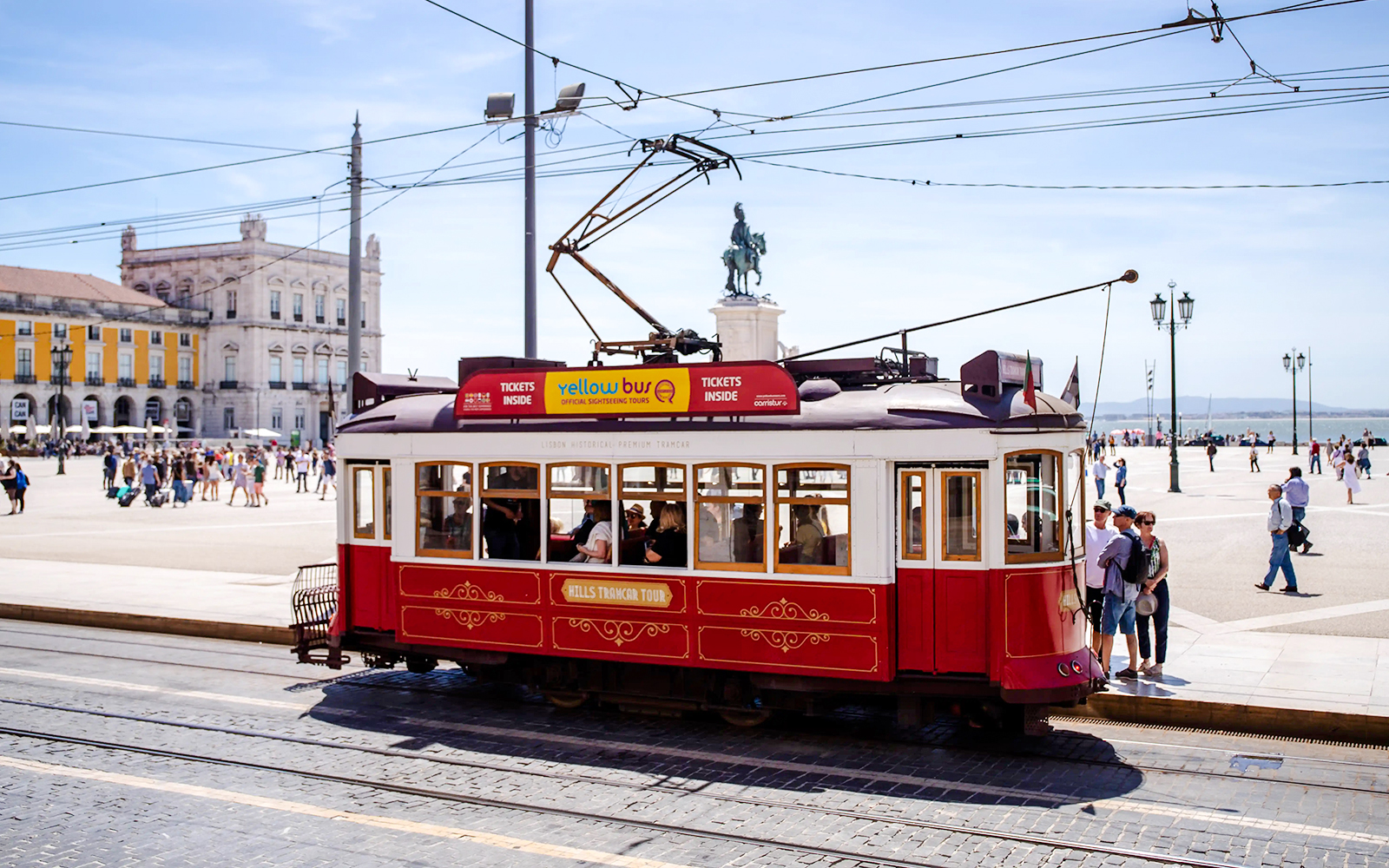 Lisbon tram in Praça do Comércio with tourists boarding.