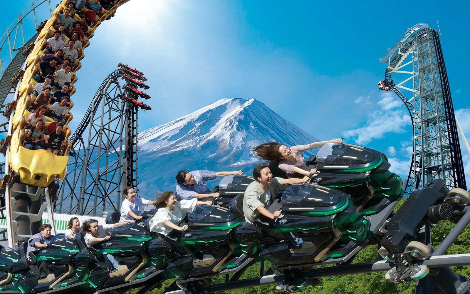 People enjoying a rollercoaster ride at Fuji-Q Highland with Mount Fuji in the background.