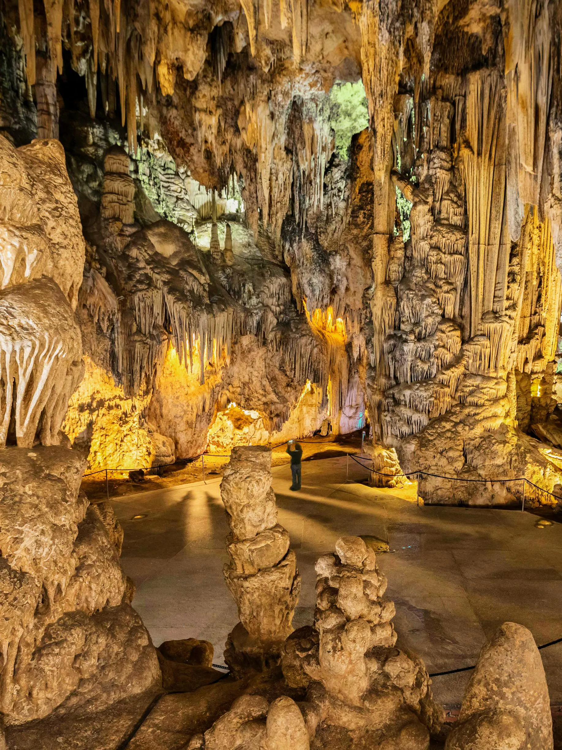Stalactites and stalagmites in Nerja Cave, Spain, with a visitor exploring the formations.