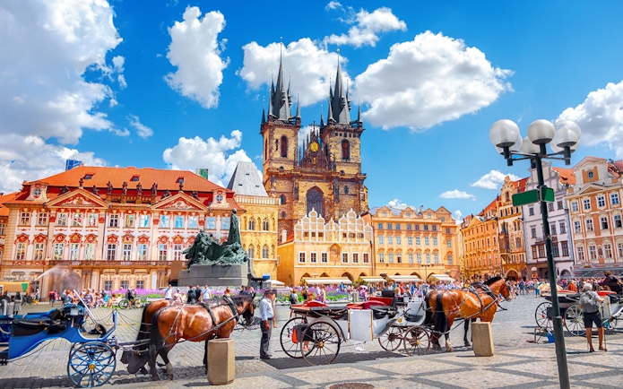 Horse-drawn carriages in Old Town Square, Prague, with Týn Church in the background.