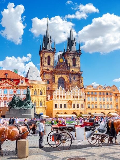 Horse-drawn carriages in Old Town Square, Prague, with Týn Church in the background.