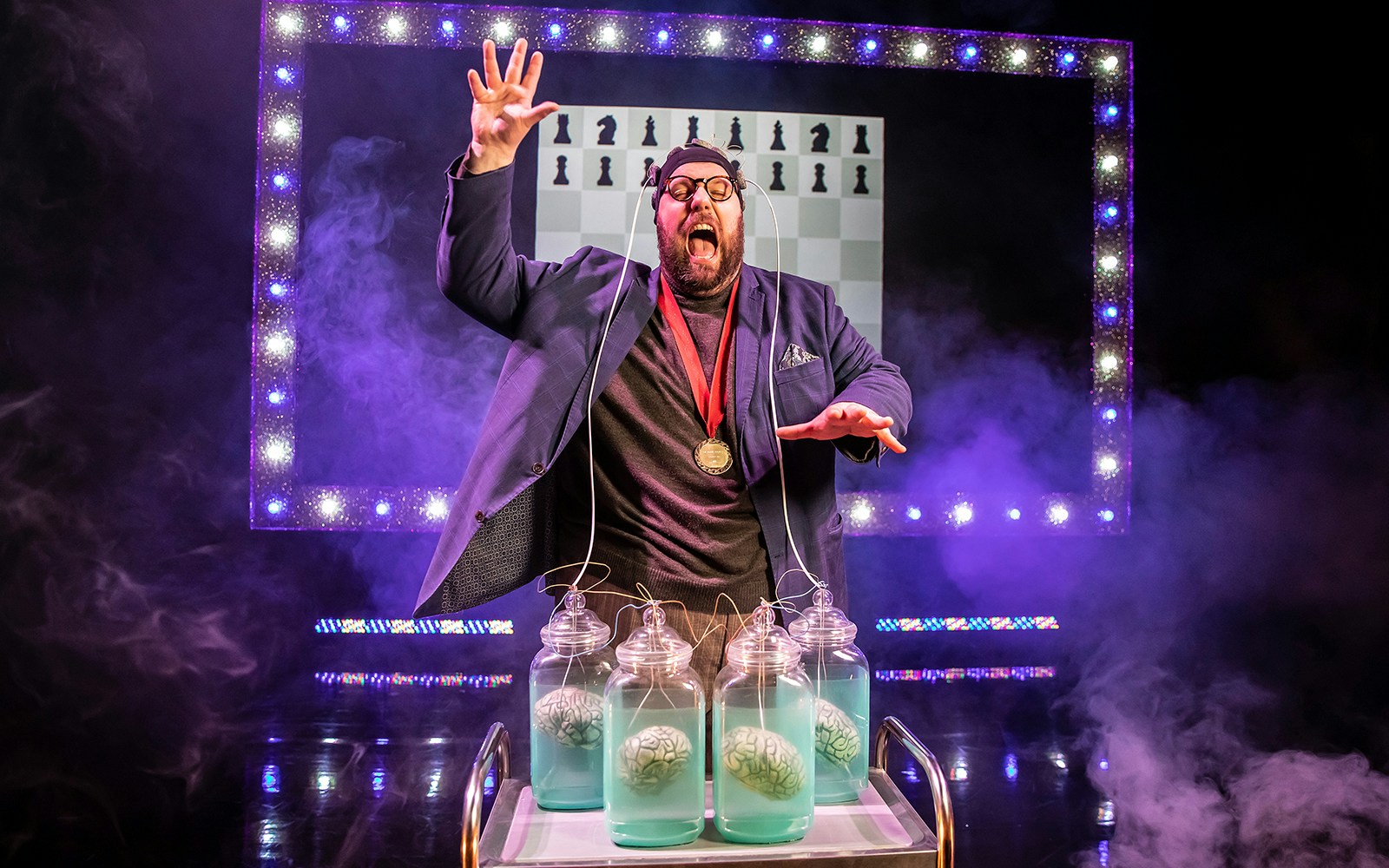 Mind Mangler performing with brains in jars on stage, Tragic Circle show.