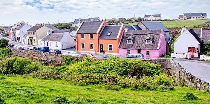 Colorful houses along a street in Doolin Village, Ireland, with lush greenery in the foreground.