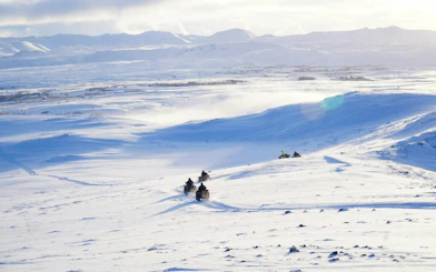 ATVs driving on snowy terrain with mountain views during Twin Peaks tour in Reykjavik.