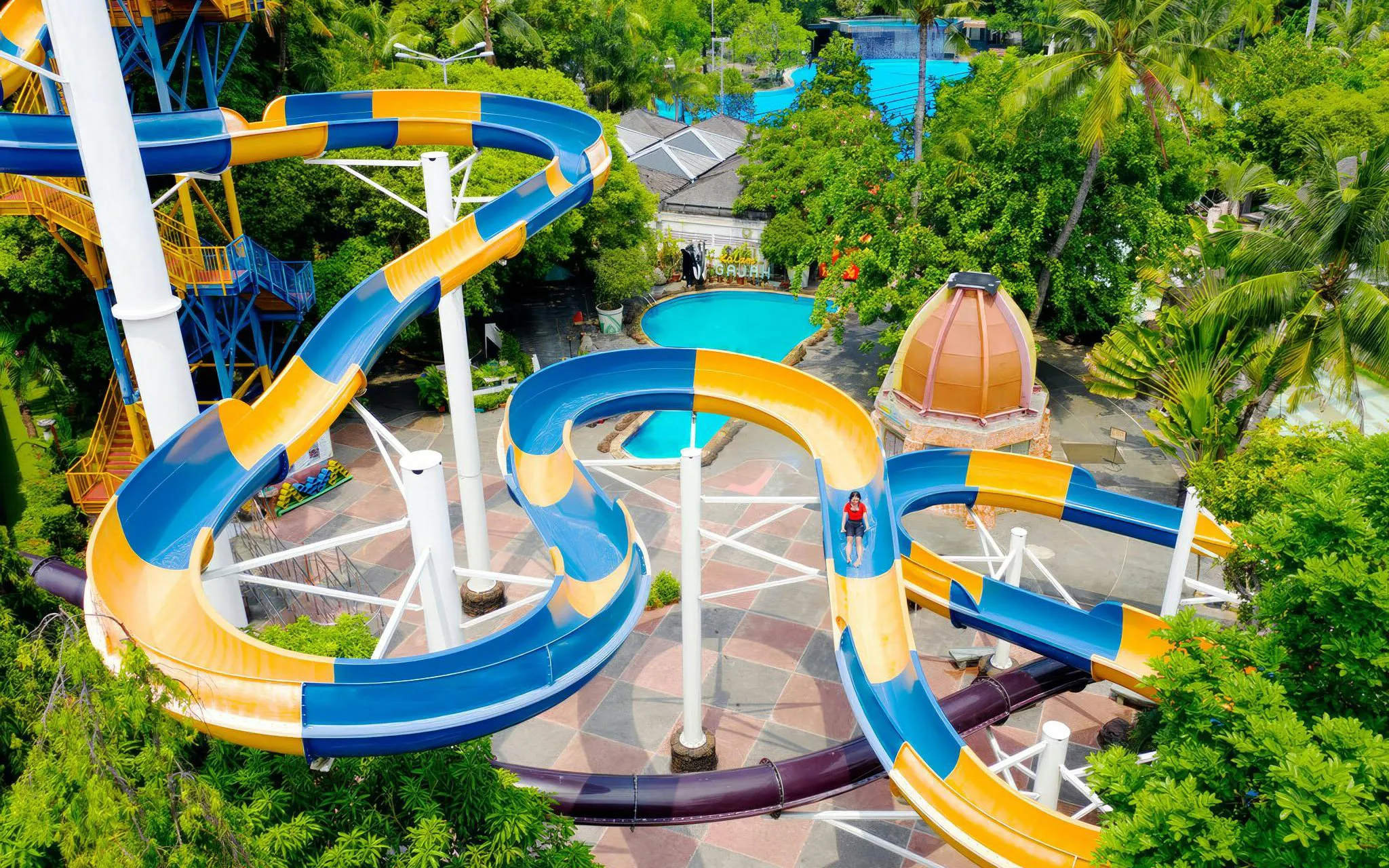 Spiral water coaster at Atlantis Water Adventure Park Ancol with lush greenery.