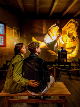 Couple watching Rembrandt projection at Amsterdam museum exhibit.