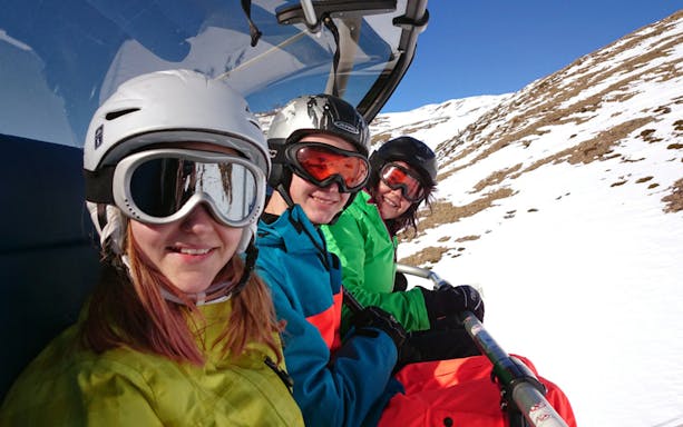 Skiers on a chairlift with snowy mountain backdrop, Krakow skiing tour.