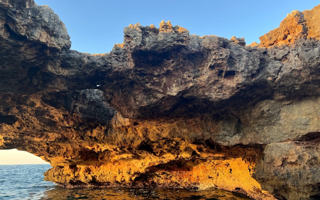 Polignano a Mare coastal rock formations at sunset.