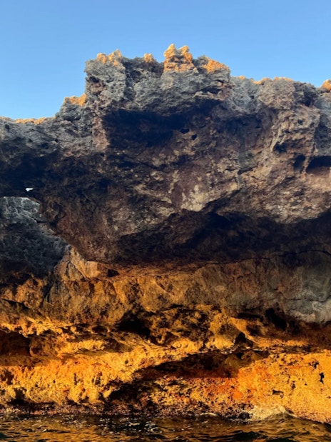 Polignano a Mare coastal rock formations at sunset.