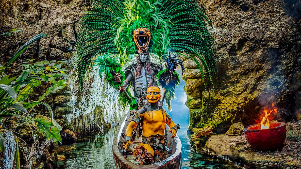 Performers in traditional Mayan attire on a canoe at Xcaret Park, Mexico.