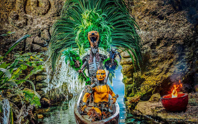 Performers in traditional Mayan attire on a canoe at Xcaret Park, Mexico.