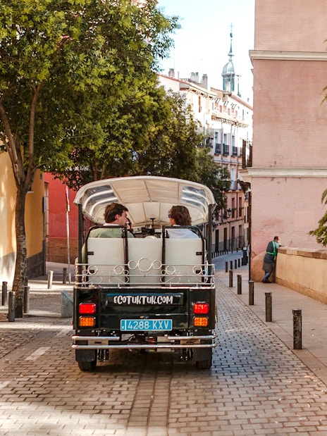 Electric tuk-tuk on a cobblestone street in Madrid, Spain.