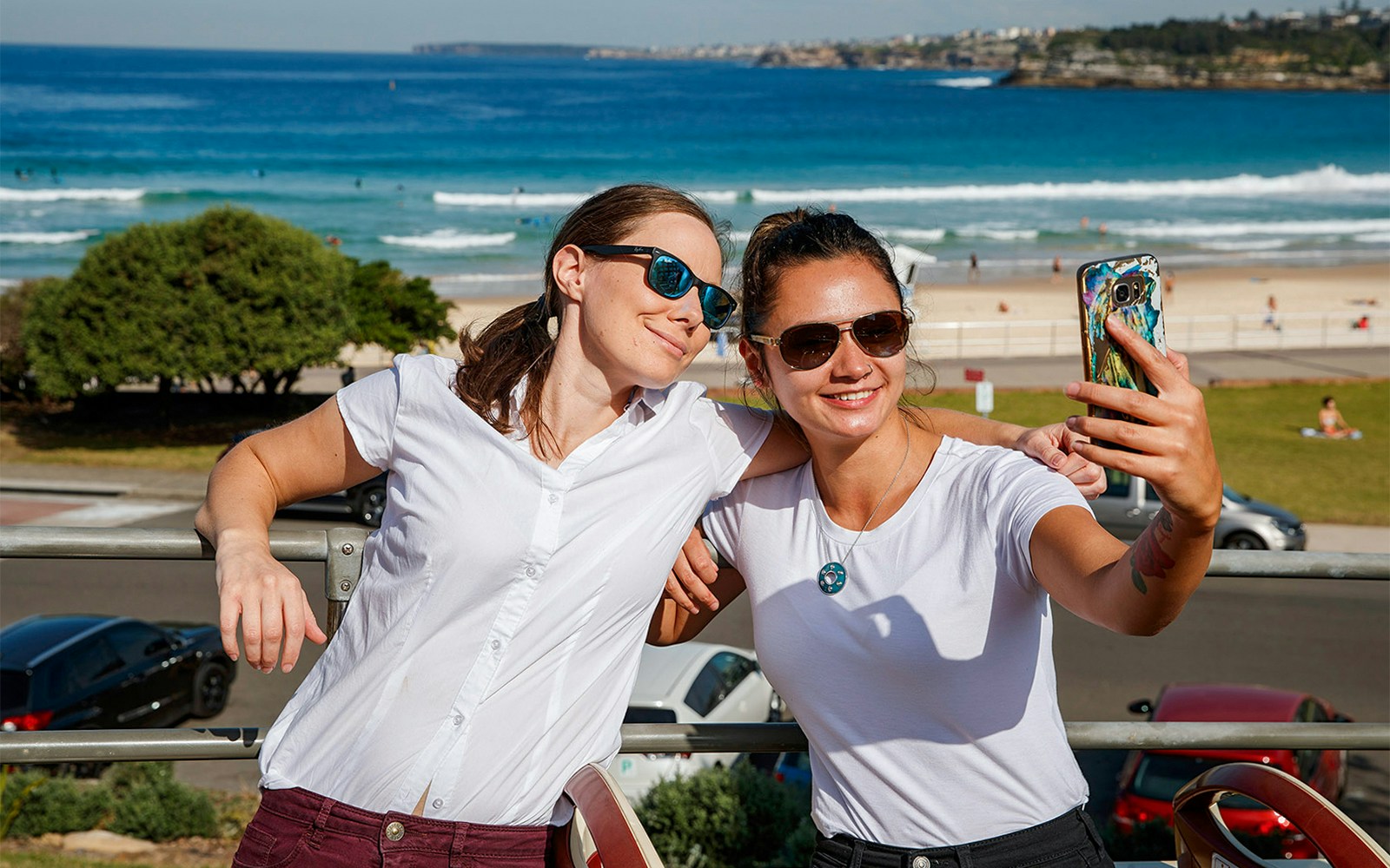 Passengers taking a selfie on Big Bus Sydney with Bondi Beach in the background.
