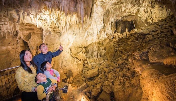 Family exploring stalactites in Aranui Cave, New Zealand.