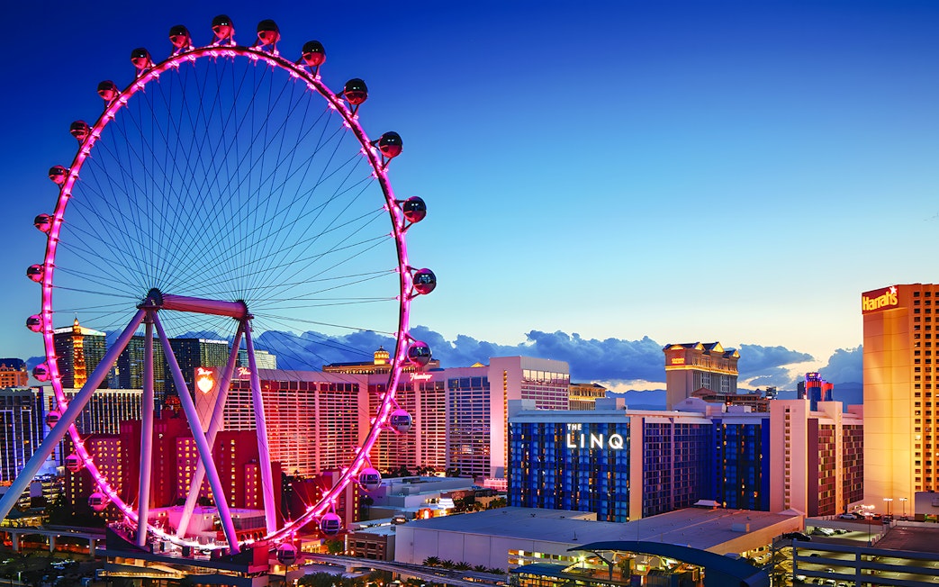 High Roller Wheel illuminated at dusk, Las Vegas skyline in background.