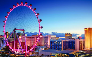High Roller Wheel illuminated at dusk, Las Vegas skyline in background.