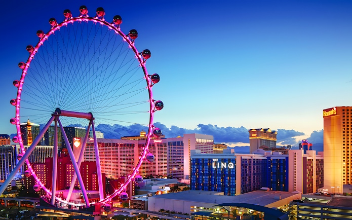 High Roller Wheel illuminated at dusk, Las Vegas skyline in background.