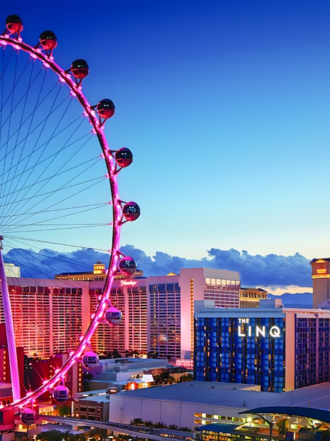 High Roller Wheel illuminated at dusk, Las Vegas skyline in background.