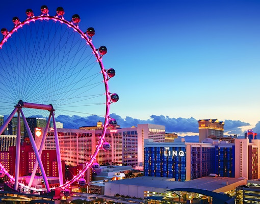 High Roller Wheel illuminated at dusk, Las Vegas skyline in background.