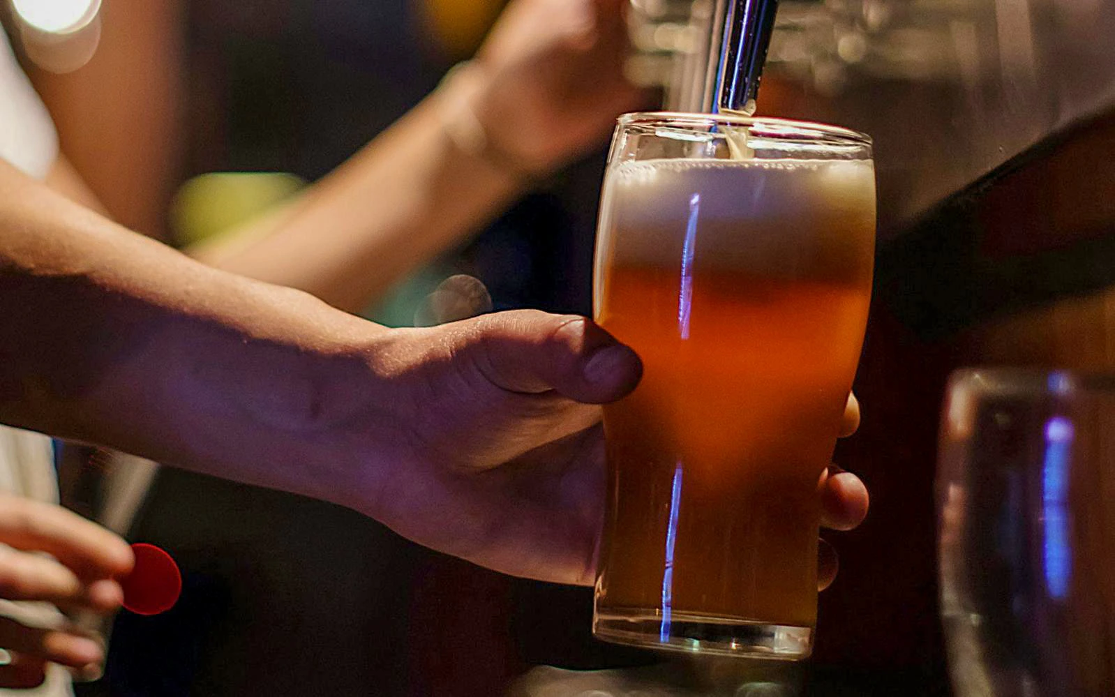 Hand pouring beer into a glass during a brewery tour with lunch and tasting.