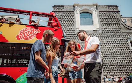 Tourists with a guide in front of a City Sightseeing bus in Naples.