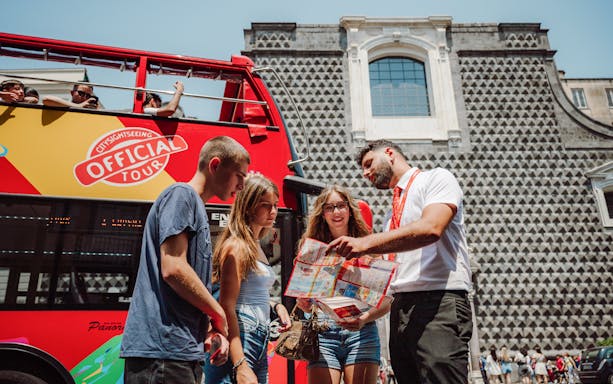Tourists with a guide in front of a City Sightseeing bus in Naples.