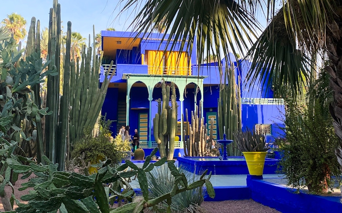 Jardin Majorelle's vibrant blue villa surrounded by tall cacti and lush greenery in Marrakech.