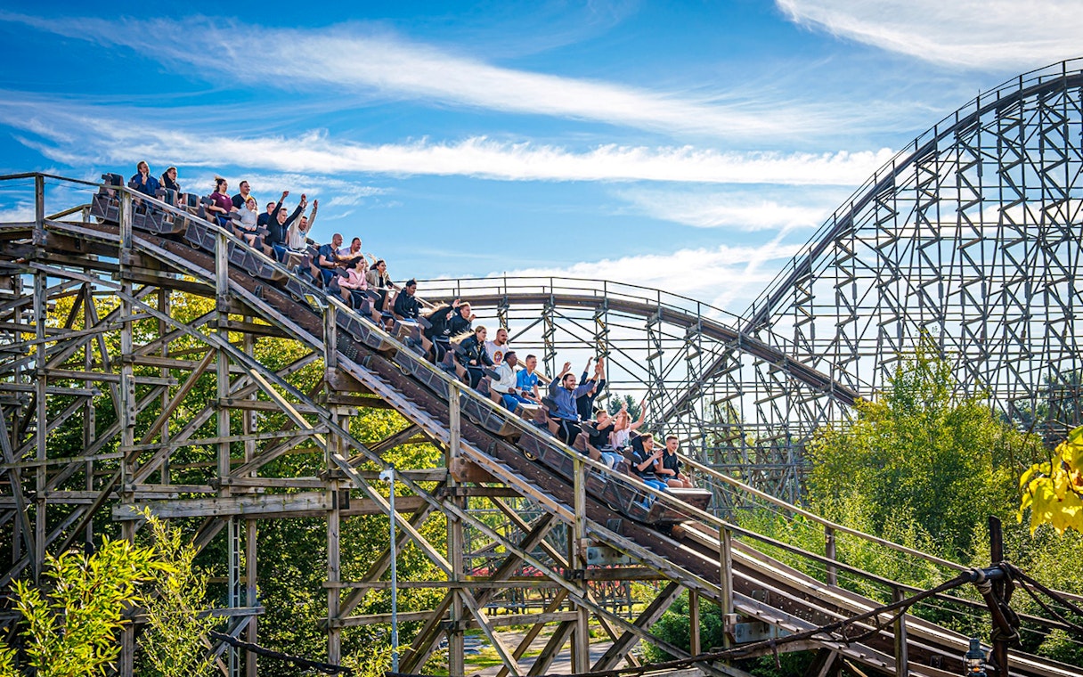 Roller coaster at Heide Park with riders descending a wooden track.