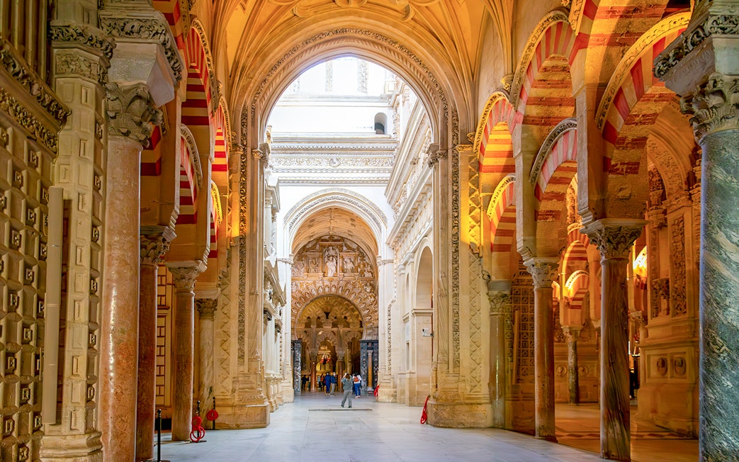 Visitors exploring the arches and columns inside Cordoba Mosque-Cathedral.