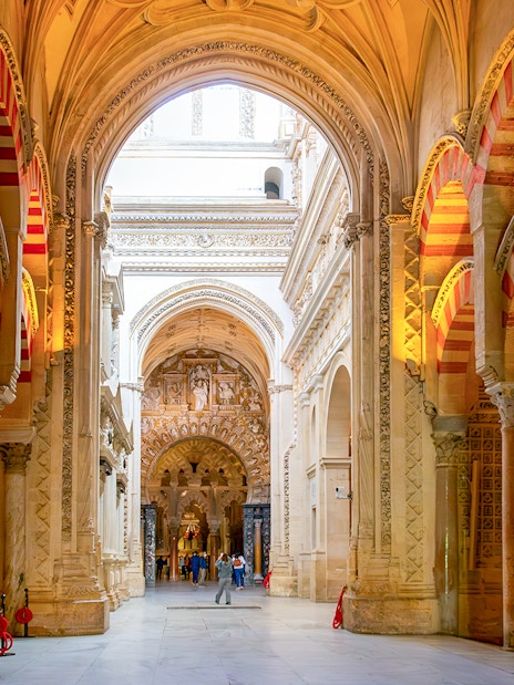 Visitors exploring the arches and columns inside Cordoba Mosque-Cathedral.