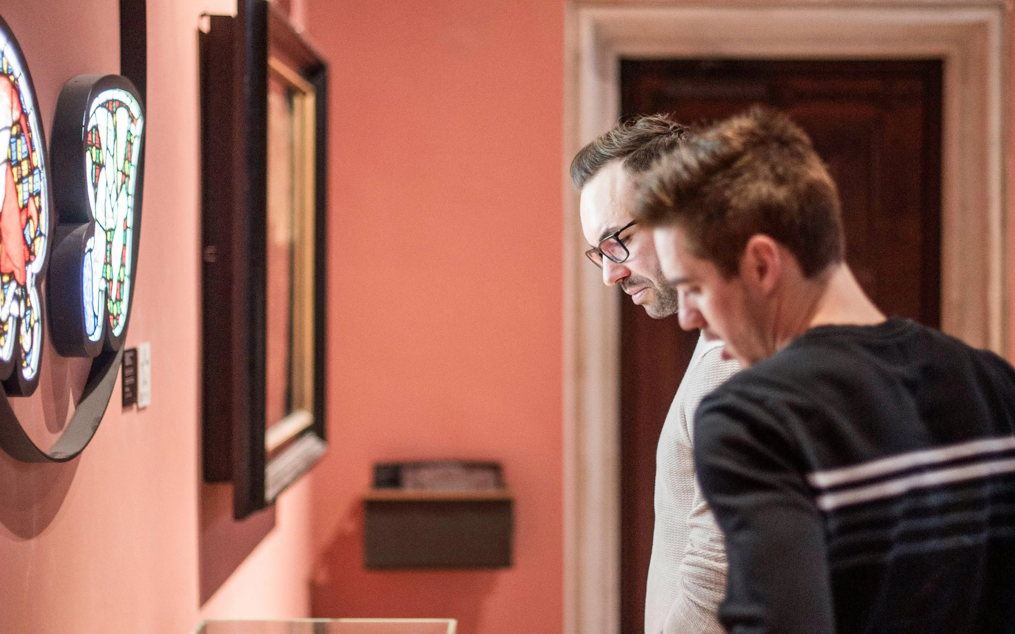 Visitors examining stained glass art at Gruuthusemuseum, Bruges.