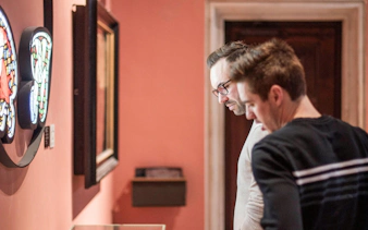 Visitors examining stained glass art at Gruuthusemuseum, Bruges.