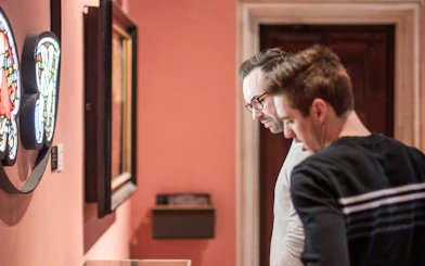 Visitors examining stained glass art at Gruuthusemuseum, Bruges.